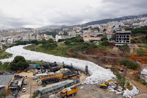 Trucks are seen next to piles of garbage in Jdeideh, a Beirut suburb, ahead of moving it to the country's largest landfill of Naameh, just south of the Lebanese capital